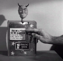 From the Twilight Zone episode 'Nick of Time', a screenshot of a novelty fortune teller. It's a napkin dispenser with a devil's head on top.